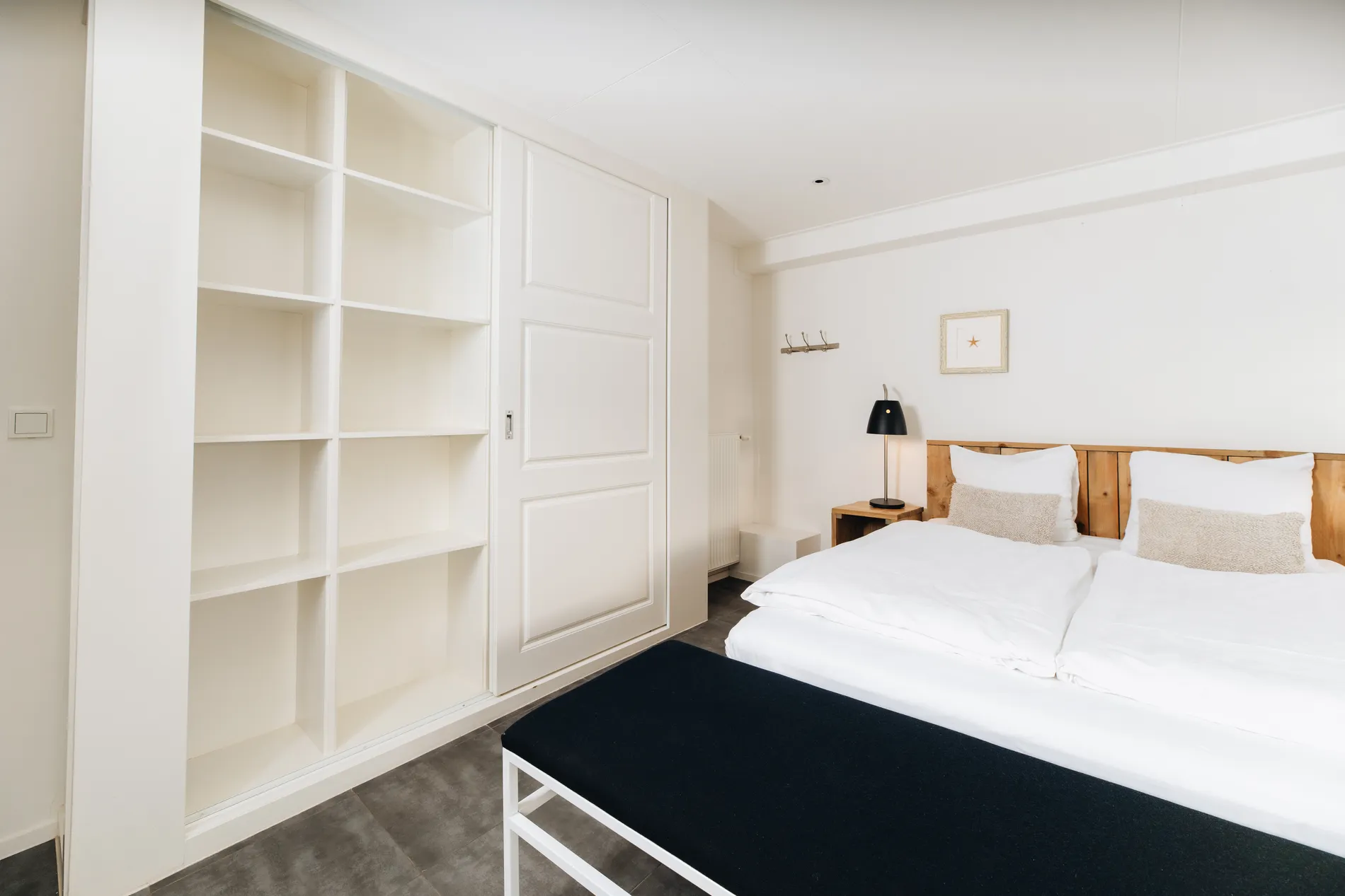 Slaapkamerinterieur met focus op de grote witte inbouwkast en het comfortabele bed.